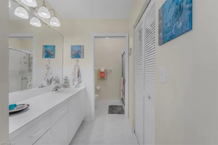 Full bath with a closet, vanity, a stall shower, and hanging lights