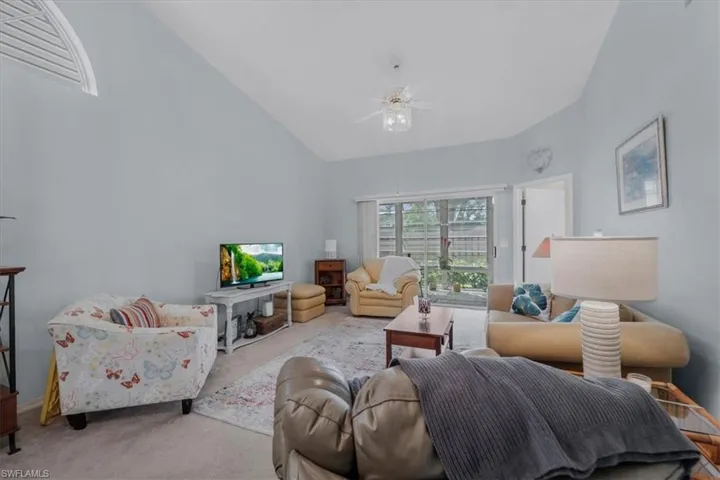Living room featuring carpet flooring, ceiling fan, and vaulted ceiling