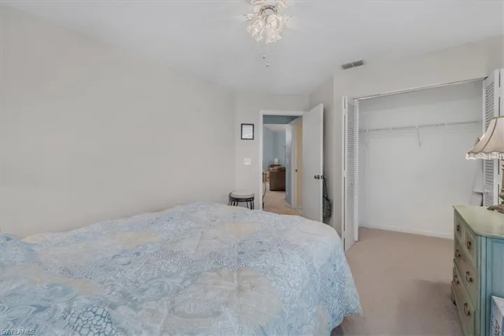 Bedroom featuring light carpet, a ceiling fan, and a closet