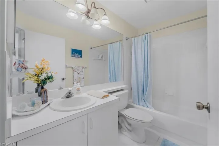 Bathroom featuring vanity, shower / tub combo with curtain, hanging lights, and tile patterned flooring