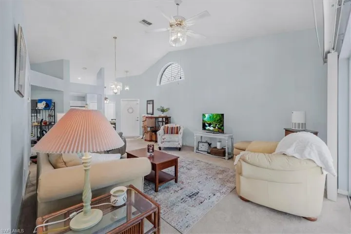 Living area featuring carpet, vaulted ceiling, a ceiling fan, and suspended lighting