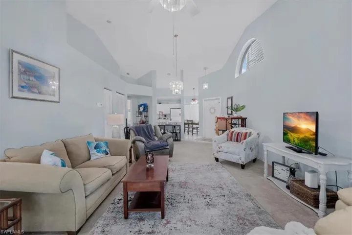 Living area featuring carpet, vaulted ceiling, a ceiling fan, plenty of natural light, and suspended lighting