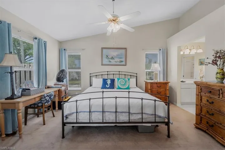 Bedroom featuring lofted ceiling, light carpet, ceiling fan, and connected bathroom