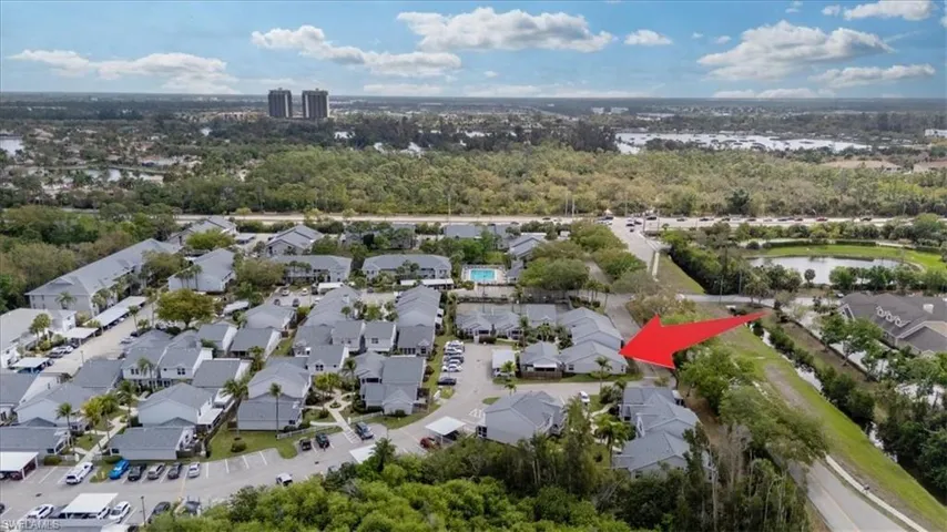 Aerial perspective of suburban area featuring a nearby body of water and a tree filled landscape