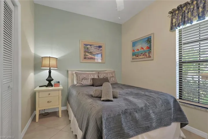 Bedroom featuring tiled flooring, a louvered bifold closet door, and an angled ceiling