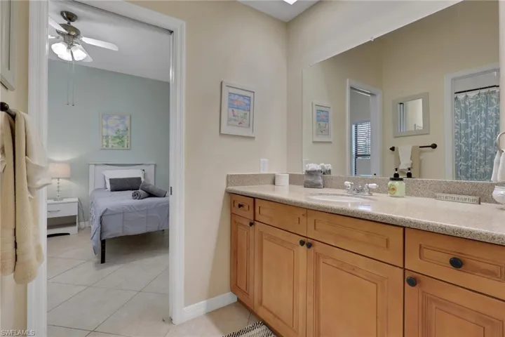 Bathroom vanity with light wood cabinetry, stone-finish countertop, and integrated sink