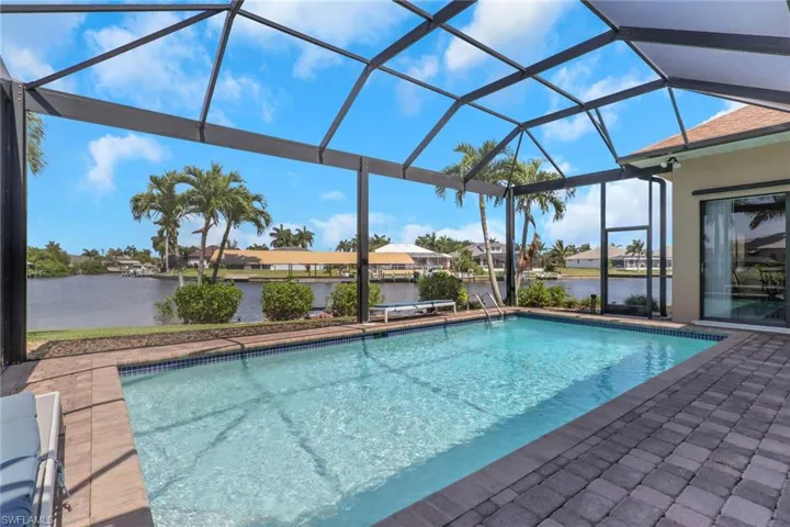 Screened pool enclosure featuring a rectangular swimming pool with integrated steps, surrounded by paver decking