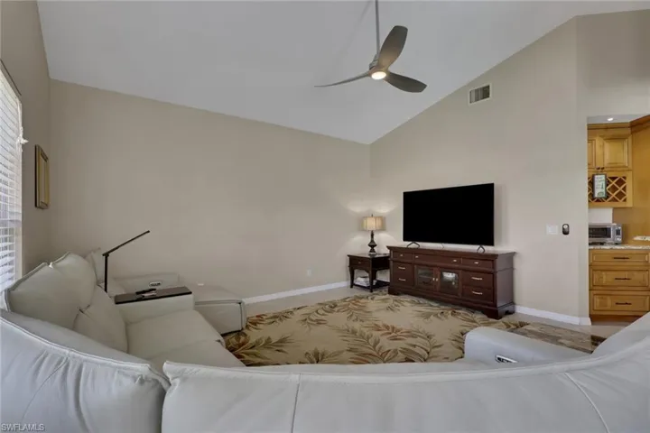 Vaulted ceiling with a contemporary ceiling fan, light-toned walls, and a built-in media console