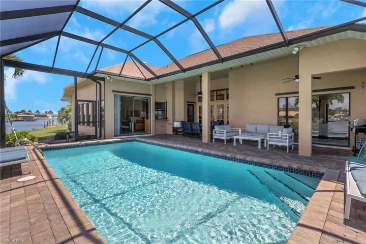 Screen-enclosed swimming pool with brick paver decking