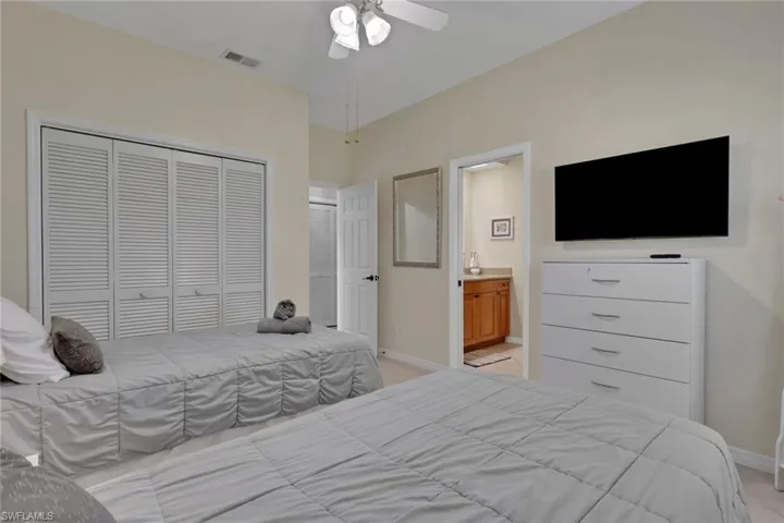 Bedroom featuring neutral wall paint, louvered closet doors, and a ceiling fan with integrated lighting