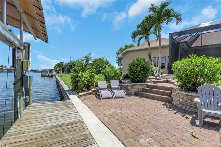 Waterfront paver patio featuring a private dock with boat lift