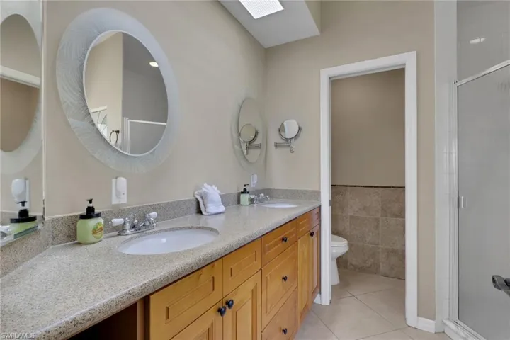 Dual vanity featuring light-colored stone-finish countertops, wood cabinetry, and under-mount sinks