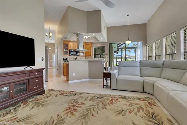 Expansive living area featuring vaulted ceilings, tile flooring, and multiple windows with horizontal blinds