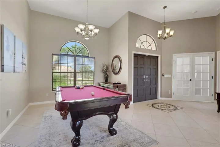 Entry area featuring high ceilings with two chandeliers, arched transom windows, tile flooring, and double entry doors