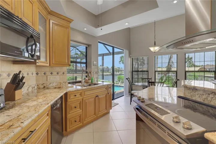 Kitchen featuring light wood cabinetry, stone countertops, and a tiled backsplash