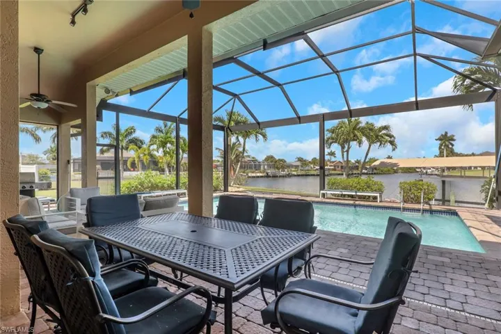 Screened lanai featuring a built-in ceiling fan, paver flooring, and a water-facing swimming pool