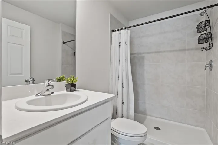Bathroom with a tile shower, vanity, and toilet
