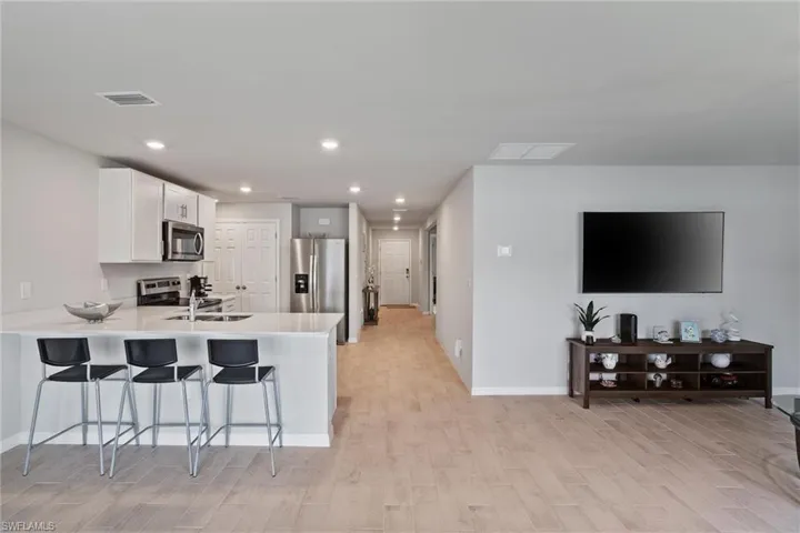 Kitchen featuring stainless steel appliances, light wood-style flooring, a peninsula, a kitchen breakfast bar, and baseboards