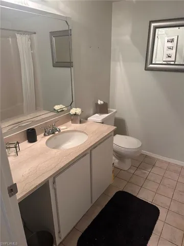 Bathroom featuring tile patterned floors, toilet, vanity, baseboards, and curtained shower