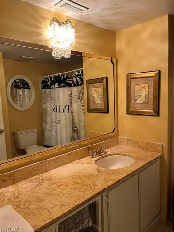 Full bathroom featuring toilet, a notable chandelier, visible vents, and vanity
