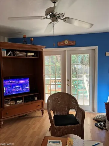 Living room with wood finished floors, ceiling fan, and a healthy amount of sunlight