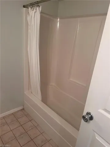 Full bath featuring tile patterned floors, baseboards, and shower / tub combo