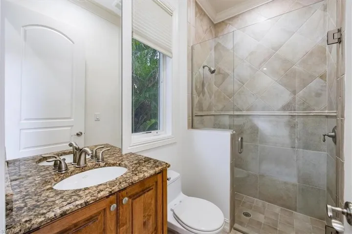 Guest bathroom with granite countertop, toilet and shower.