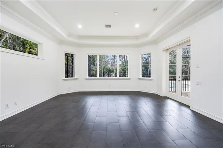 Large primary bedroom with tile floors, windows/sliders for natural light and access to the pool/spa/lanai.