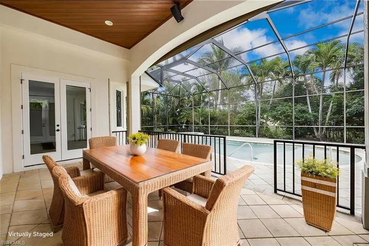 Virtually Staged - Covered area with wood ceiling, pavers and french doors with views of the pool/spa/enclosed lanai.