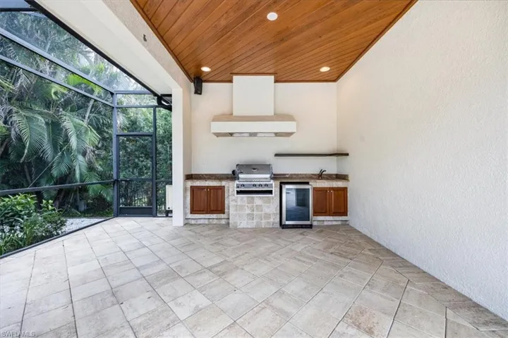 Outdoor kitchen with grill & vent hood, beverage cooler, sink and storage.