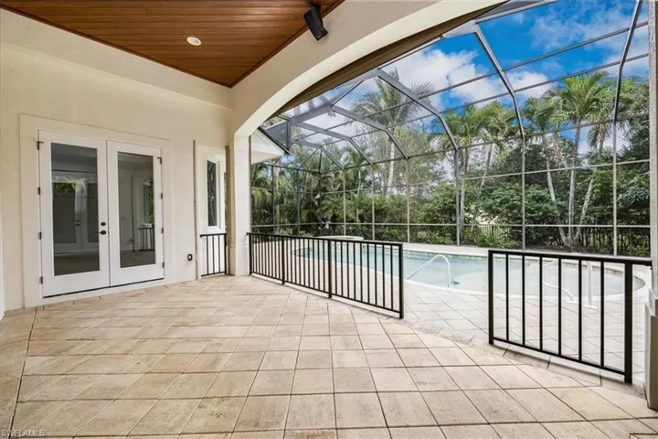 Covered area with wood ceiling, pavers and french doors with views of the pool/spa/enclosed lanai.