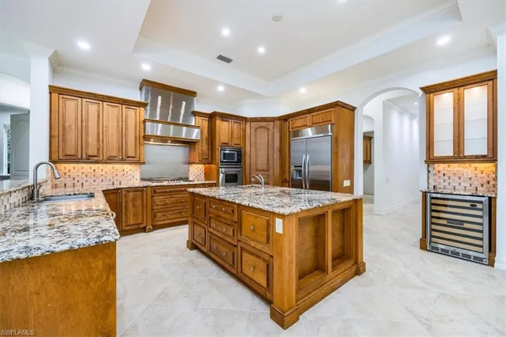 Kitchen with large center island, granite countertops with wood cabinetry and stainless steel appliances.