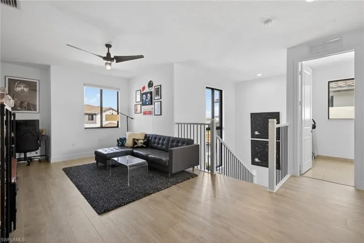 Living room with a desk, light wood-type flooring, a ceiling fan, and a textured ceiling