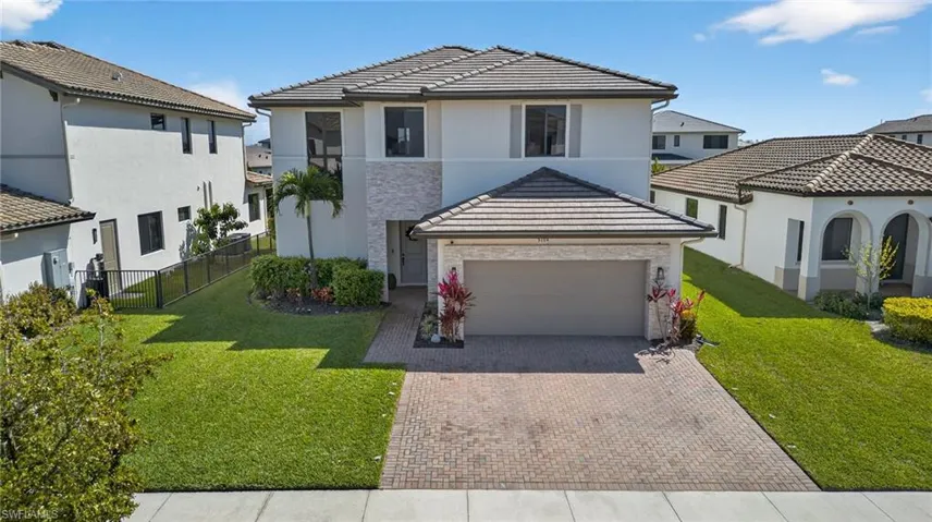 View of front of house featuring decorative driveway, stucco siding, an attached garage, and a residential view