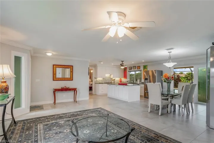 Living room with light tile patterned flooring, crown molding, and ceiling fan