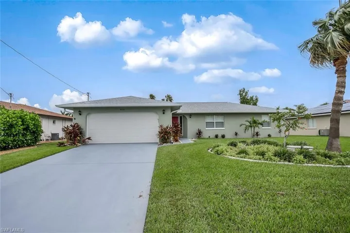 Single story home with a garage and a front lawn