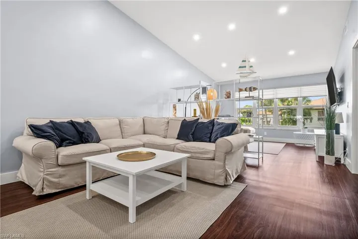 Living area with dark wood finished floors, recessed lighting, and high vaulted ceiling