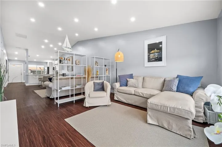 Living room with recessed lighting, dark wood finished floors, and vaulted ceiling