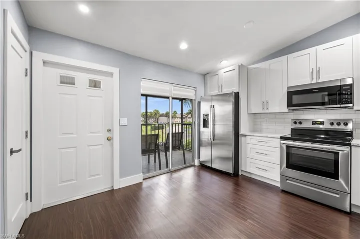 Kitchen featuring appliances with stainless steel finishes, white cabinetry, tasteful backsplash, dark wood-style flooring, and recessed lighting