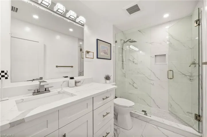 Full bathroom featuring a marble finish shower, vanity, light marble finish flooring, and recessed lighting