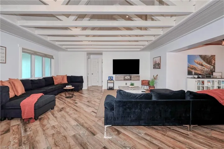 Living room with beam ceiling and wood plank tile flooring