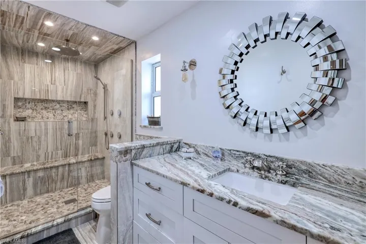Bathroom with vanity, a shower with door, and toilet