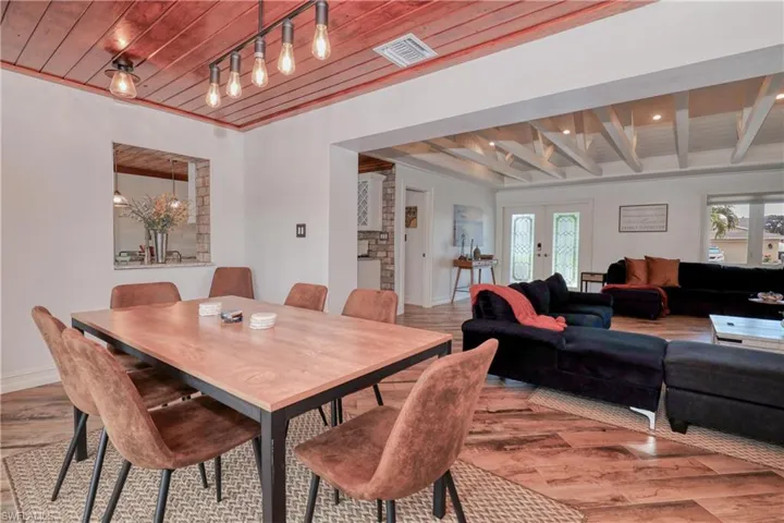 Dining space with beam ceiling, wood plank tile flooring, and track lighting
