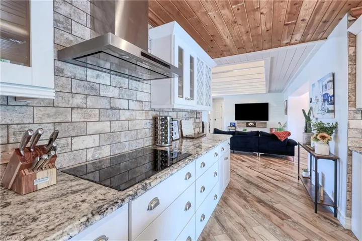 Kitchen featuring white/gray cabinets, attractive range hood, wood plank tile floors, black electric cooktop, and wood ceiling