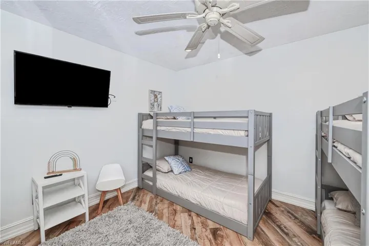 Bedroom with wood plank tile flooring, a textured ceiling, and ceiling fan