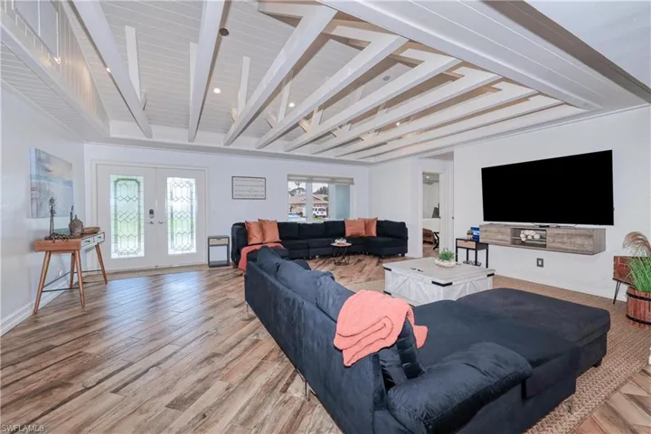 Living room with  wood plank tile floors, beamed ceiling, and french doors