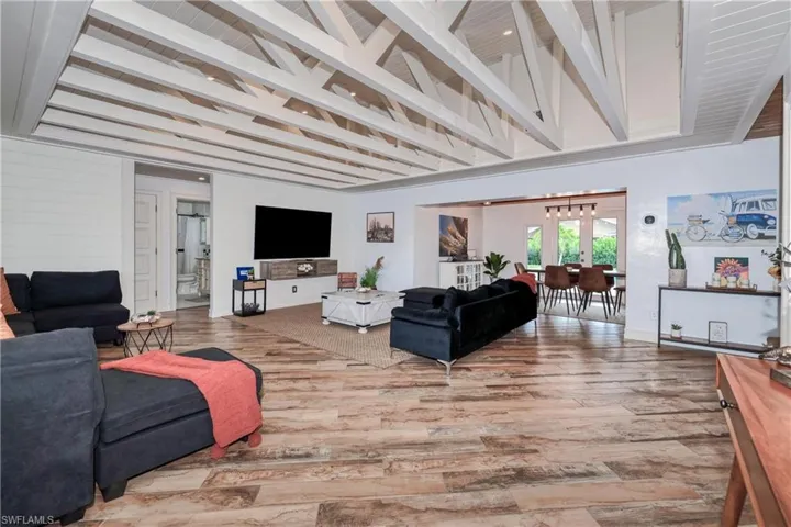 Living room featuring beam ceiling, french doors, and wood plank tile floors