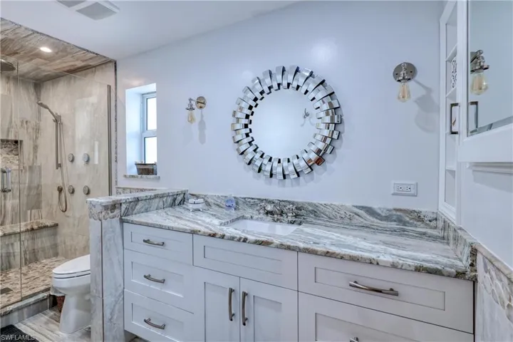 Bathroom featuring a shower with shower door, vanity, and toilet