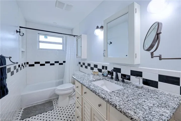 Full bathroom featuring vanity, shower / bathtub combo with decorative tile backsplash,  tile floors