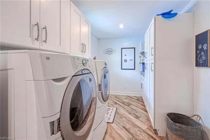 Laundry room with washing machine and dryer, wood plank tile floors, and cabinets